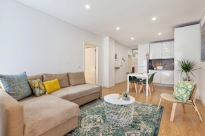 A modern living room with a beige sofa, a round coffee table, and a green patterned rug. - D&S - Porto Theater Apartment (Porto)