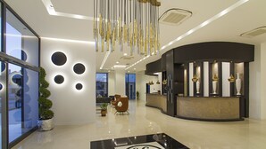 A modern lobby with a reception desk, a potted plant, and a decorative floor pattern. - Musho Hotel (Ayvalik)