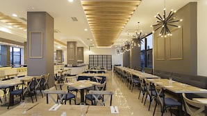 A spacious restaurant with long tables, chairs, and modern lighting fixtures. - Musho Hotel (Ayvalik)