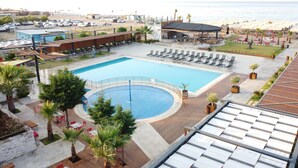 A resort pool area with sun loungers, a circular pool, and a beach view. - Musho Hotel (Ayvalik)
