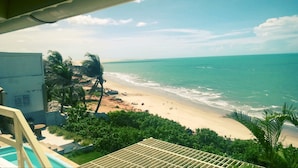 Blick auf einen Strand mit Poolbereich und Palmen.