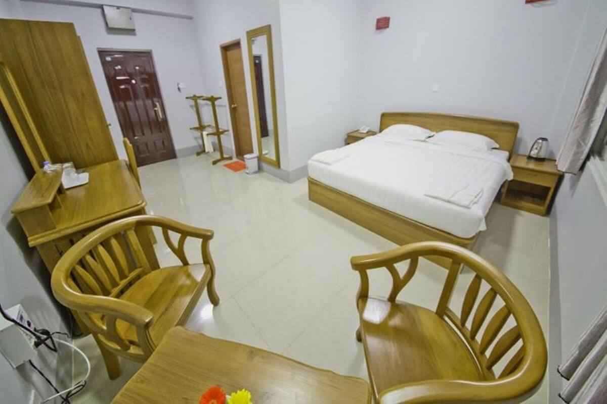 A hotel room with a bed, wooden furniture, a desk, and a chair.