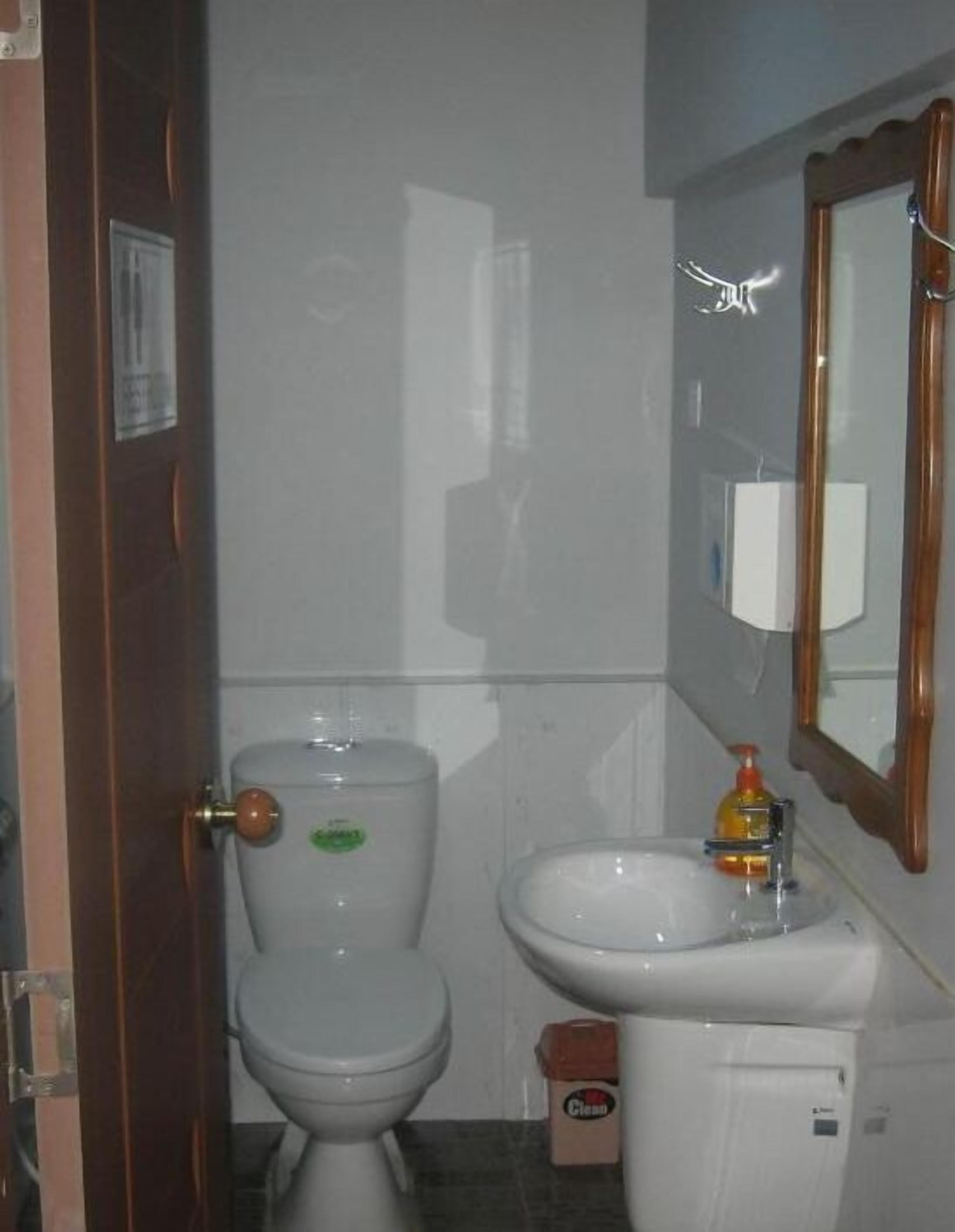 A small bathroom with a toilet, sink, and mirror.