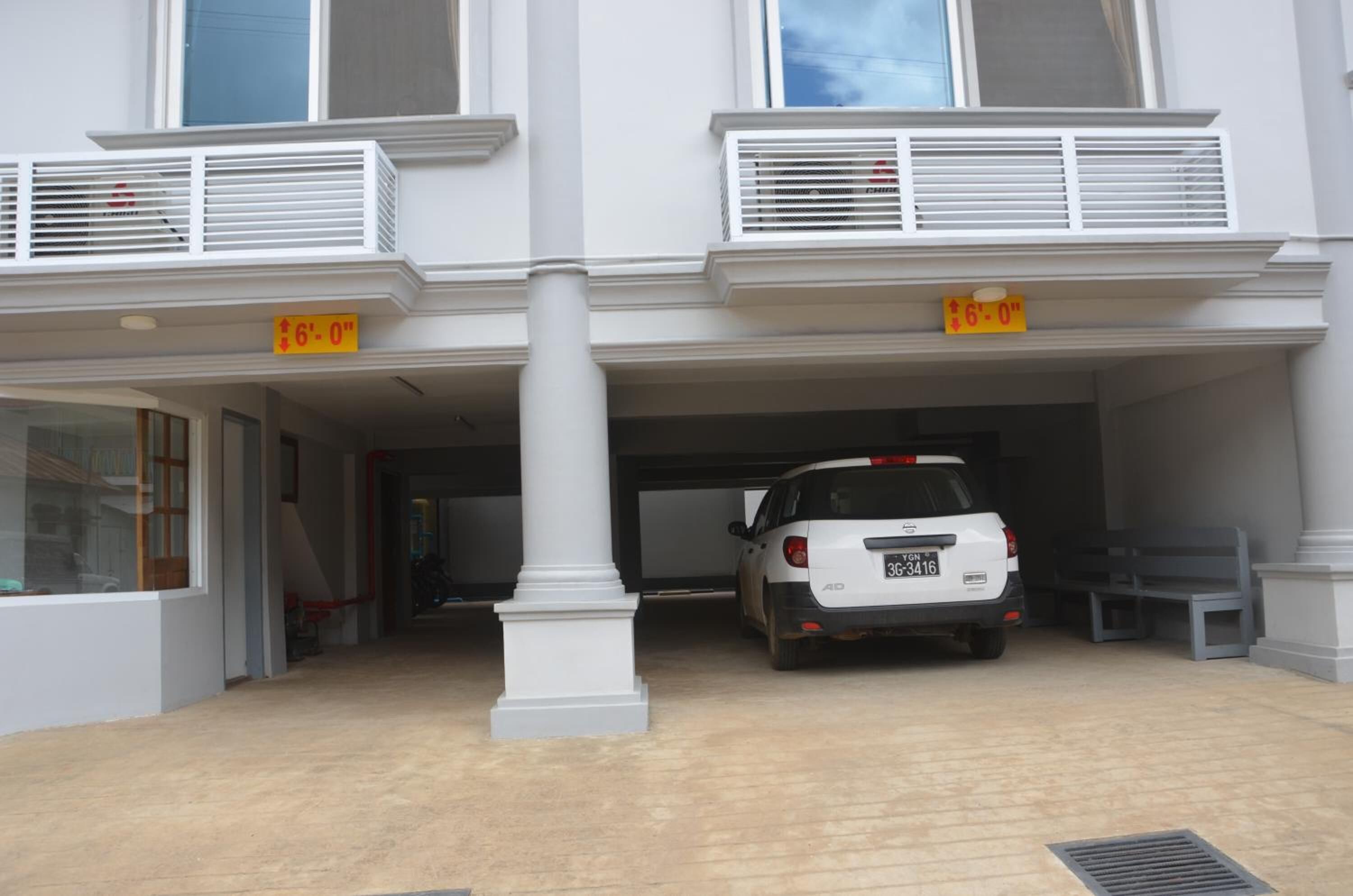 A building with a white exterior, a covered parking area, and a white car parked inside.