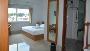 A hotel room with a bed, a wooden chair, a mirror, and a shower area. - Hotel Maymyo (Pyin Oo Lwin)