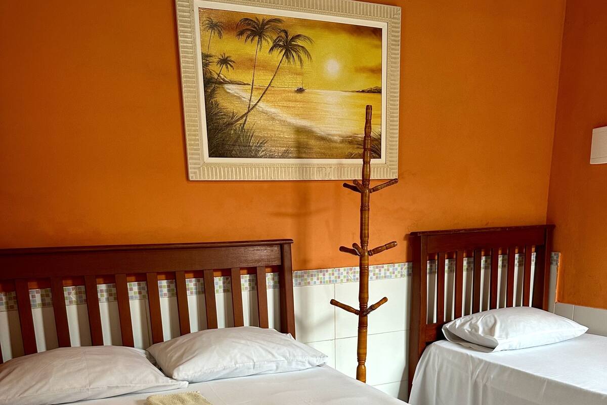 Ein Hotelzimmer mit zwei Betten, einem Sonnenuntergangsbild und einem Holz-Kleiderhaken.