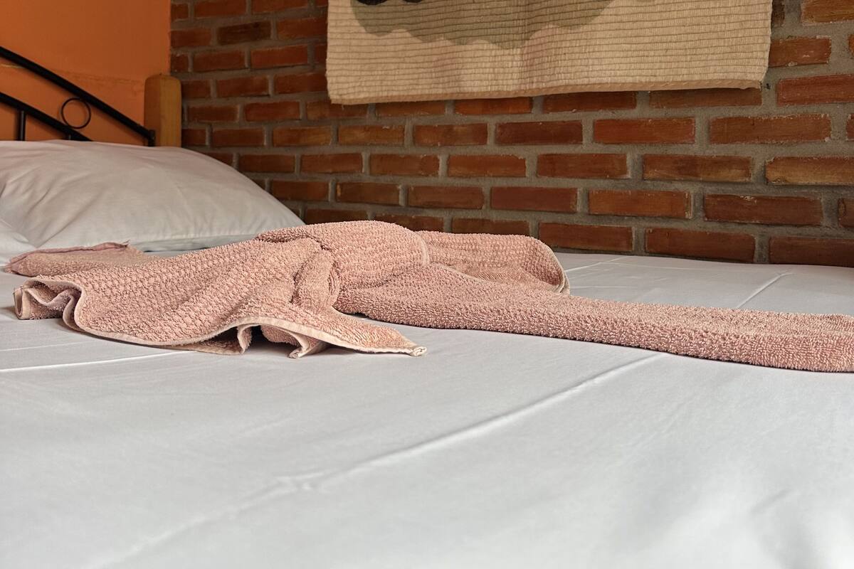 Ein Bett mit einem pinkfarbenen Handtuch und Wandteppich mit Cowboy-Motiv.