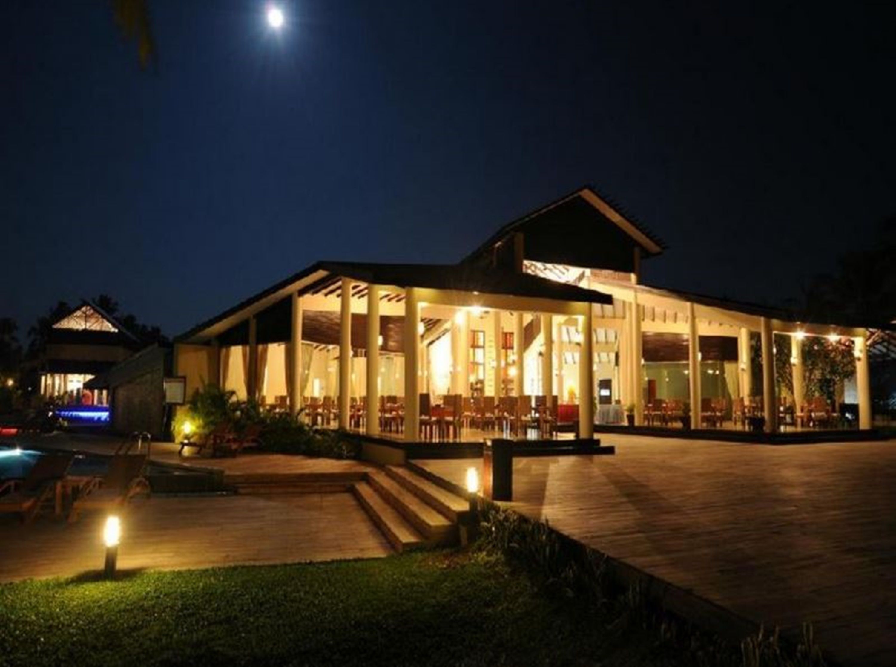 A well-lit outdoor dining area with a pool and a covered seating area.