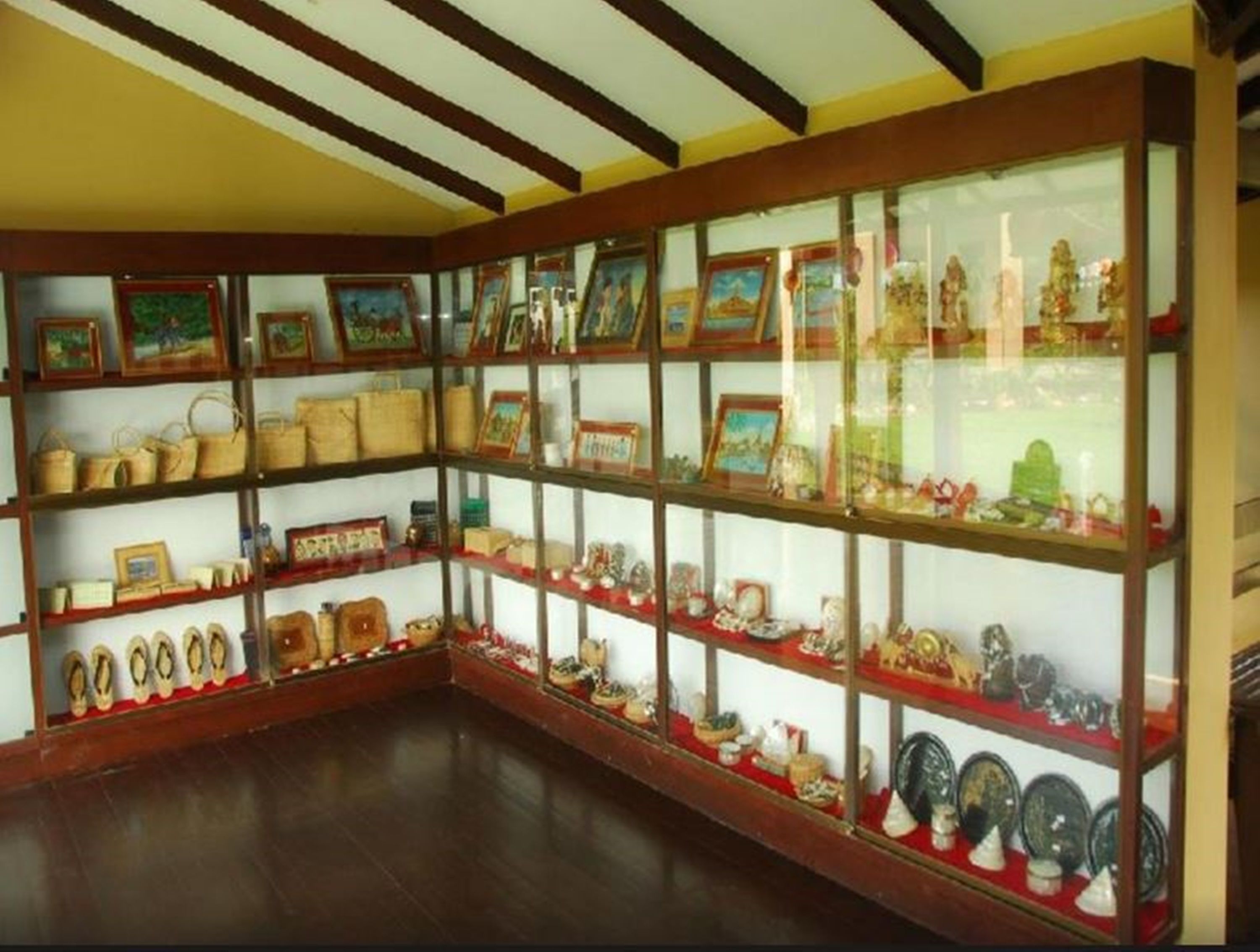 A room with wooden shelves displaying various items like framed pictures, pottery, and shoes.