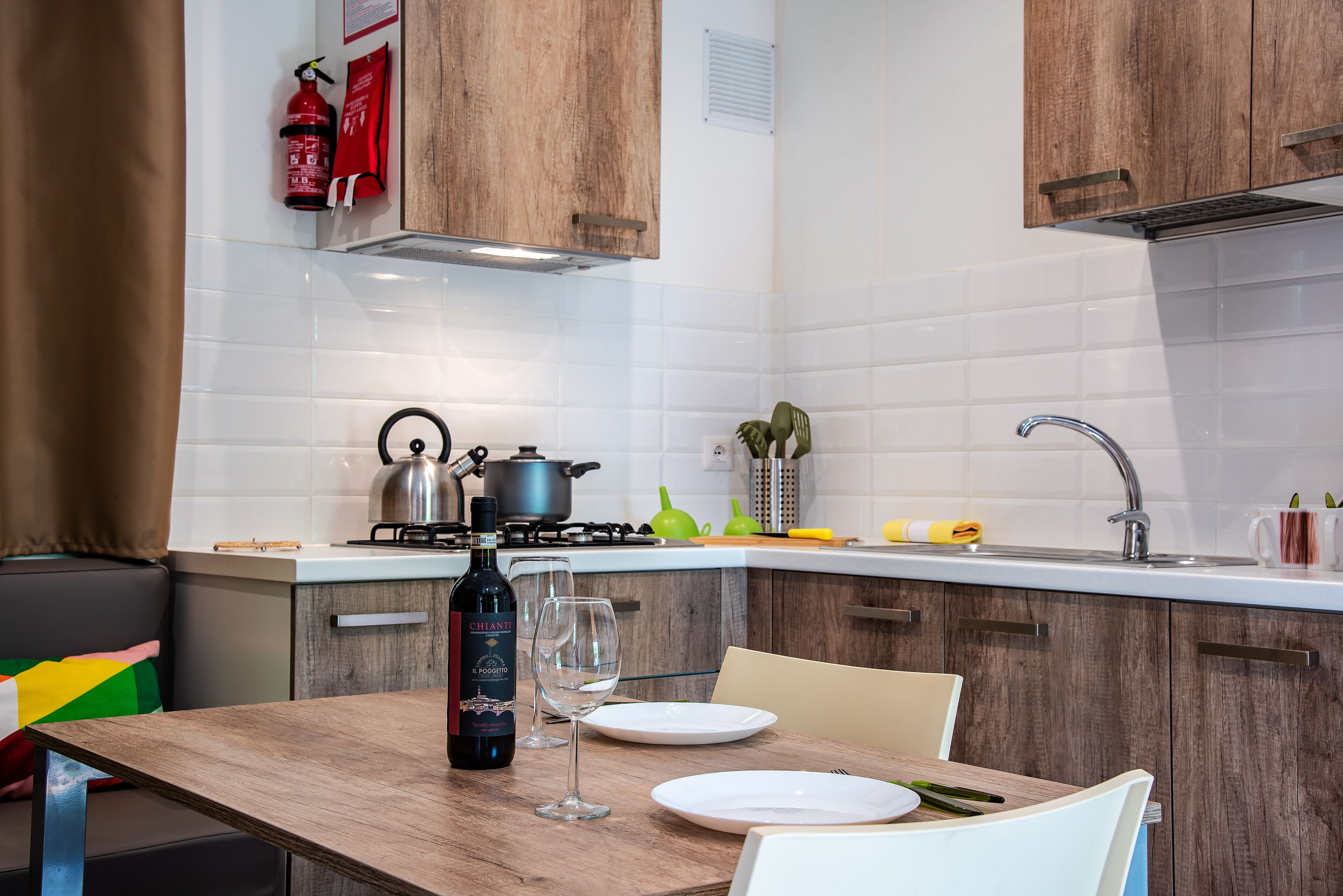 A kitchen with wooden cabinets, a gas stove, a sink, and a dining table with chairs.