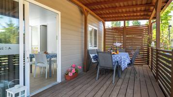 A wooden deck with a table and chairs, a potted plant, and a view of the house.
