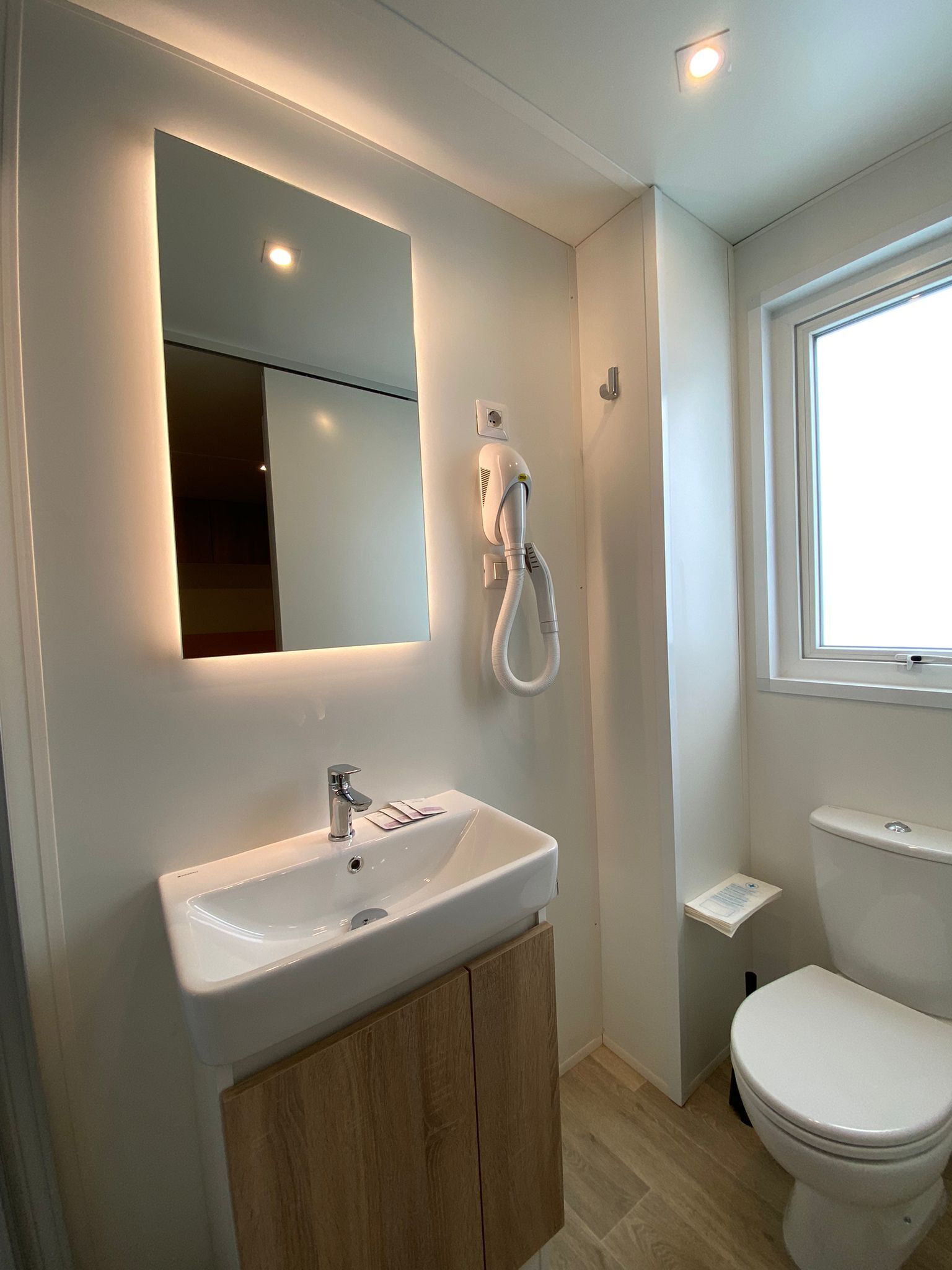 Ein modernes Badezimmer mit Waschbecken, Spiegel und Toilette in Weiß.