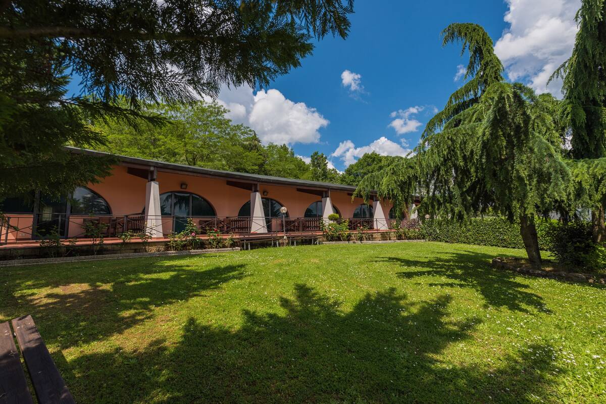 Un bâtiment doté d’une grande pelouse, d’une terrasse en bois et d’une pergola.