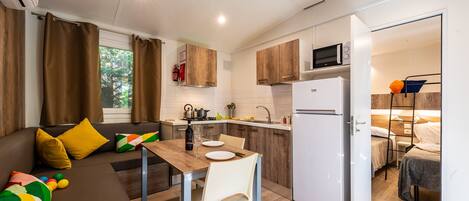 A compact kitchen with a dining area, a refrigerator, and a small sleeping area with a ladder.