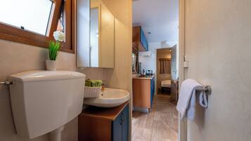 A modern bathroom with a toilet, sink, and mirror. There is a window with a view of the outside.