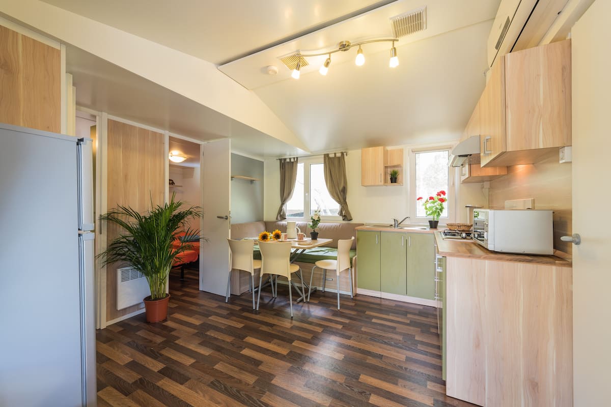 Une cuisine compacte avec un coin repas, des meubles en bois, une cuisinière encastrée et une plante en pot.