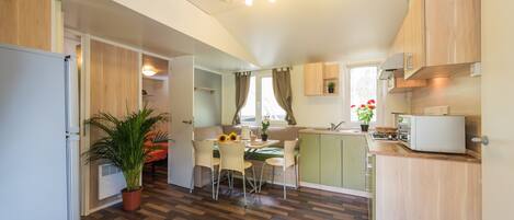 A compact kitchen with a dining area, wooden cabinets, a built-in stove, and a potted plant.