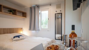 Hotelkamer met een bed, een laptop, een ontbijttafel, een spiegel en een fles drank.