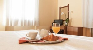 A neatly made breakfast table with a croissant, a cup of coffee, a glass of orange juice, and a teapot on a tray. - Hotel San Marco (Bedonia)