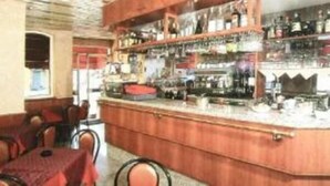 A bar area with multiple shelves of bottles, a counter, and seating with red tablecloths. - Hotel San Marco (Bedonia)