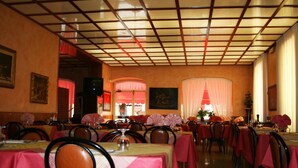 A restaurant with tables covered in red tablecloths, chairs, and a ceiling with a grid pattern. - Hotel San Marco (Bedonia)