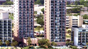 A high-rise hotel with multiple floors, a beach in the foreground, and a view of the ocean. - Palms Resort (Myrtle Beach)