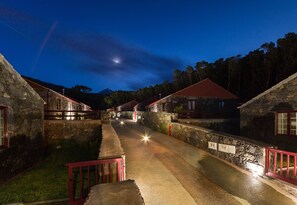 A stone building with a red roof, a paved pathway, and a stone wall with a red railing. - Aldeia das Adegas (Sao Roque do Pico)
