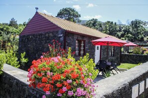 A stone building with a red roof and a small patio area with a red umbrella. - Aldeia das Adegas (Sao Roque do Pico)