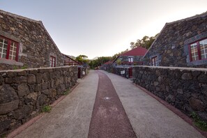 A narrow stone pathway flanked by buildings with red windows and stone walls. - Aldeia das Adegas (Sao Roque do Pico)