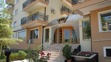 Stunning hotel building with a grand entrance, featuring a staircase, potted plants, and a beautiful flower bed.