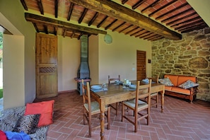 A rustic dining area with a stone wall, wooden furniture, and a chimney.