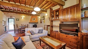 Ein gemütliches Wohnzimmer mit Kamin, Holzschränken, einer Couch und einem Fernseher.