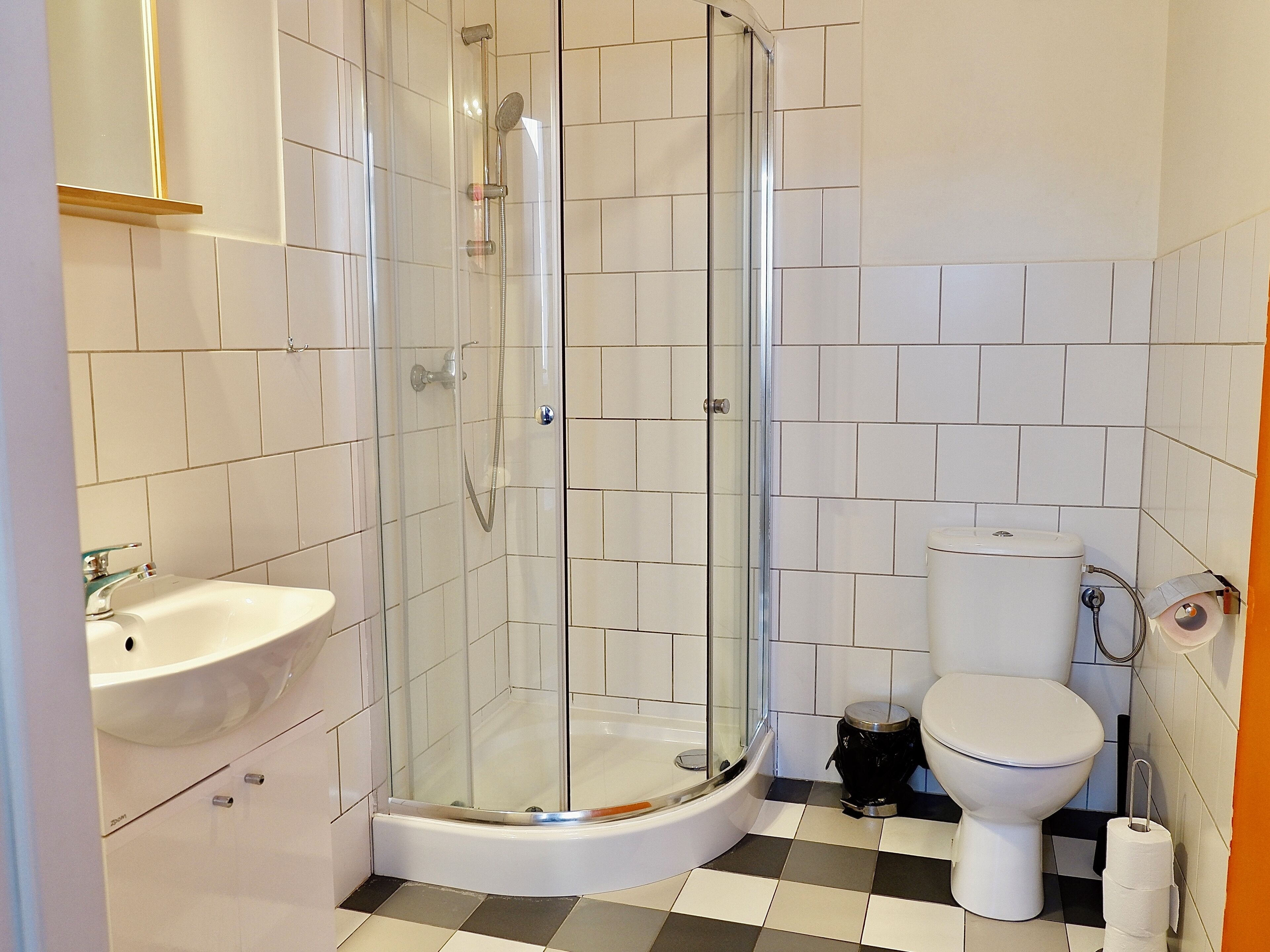 Ein Badezimmer mit einer Duschkabine, einem weißen Waschbecken und einer Toilette.