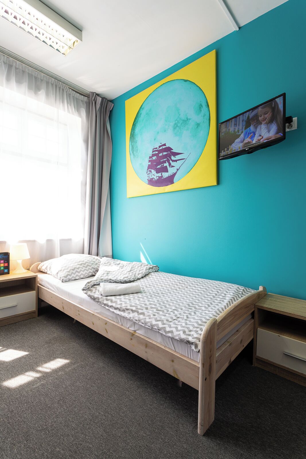 A bedroom with a bed, a nightstand, a TV, and a wall-mounted painting.