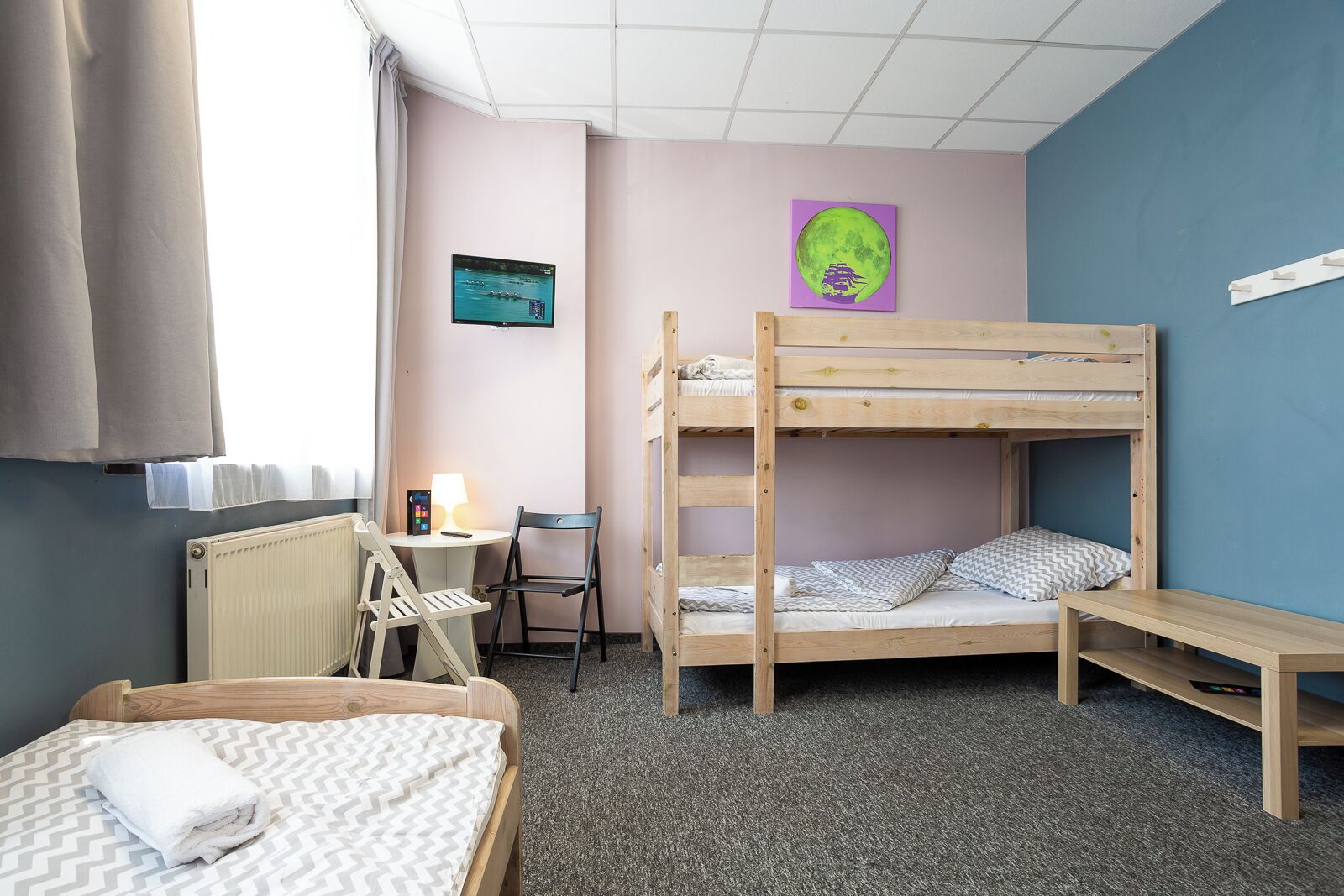 Une chambre avec des lits superposés, un bureau avec une chaise, un radiateur et une fenêtre avec des rideaux.
