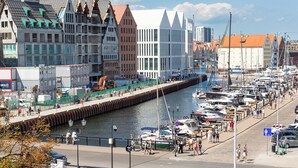 A marina with boats docked along a waterfront promenade, surrounded by historic buildings. - Moon Hostel Gdańsk (Gdansk)