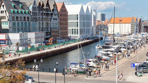 A marina with boats docked along a waterfront promenade, surrounded by historic buildings. - Moon Hostel Gdańsk (Gdansk)