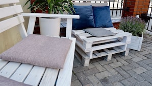 A white wooden bench with cushions, a small table with a cushion, and a potted plant. - Moon Hostel Gdańsk (Gdansk)