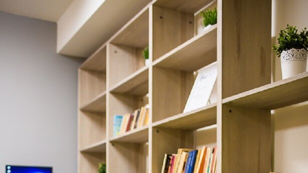 A modern office space with a bookshelf, two rocking chairs, and a computer monitor. - Moon Hostel Gdańsk (Gdansk)