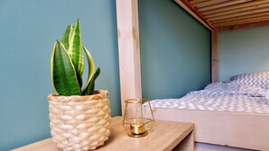 A wooden bedside table with a woven plant pot and a glass candle holder. - Moon Hostel Gdańsk (Gdansk)