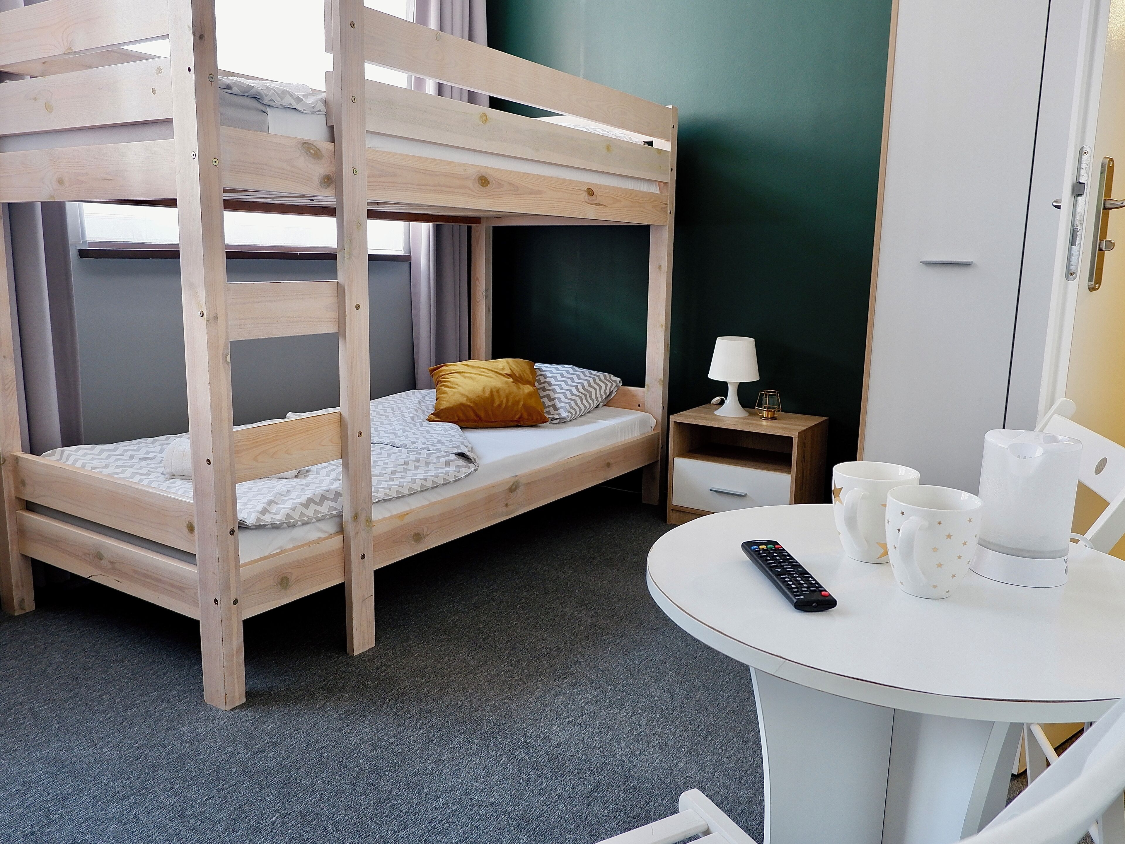 Ein Stockbett mit Nachttisch und Tisch, auf dem eine Fernbedienung und Tassen stehen.