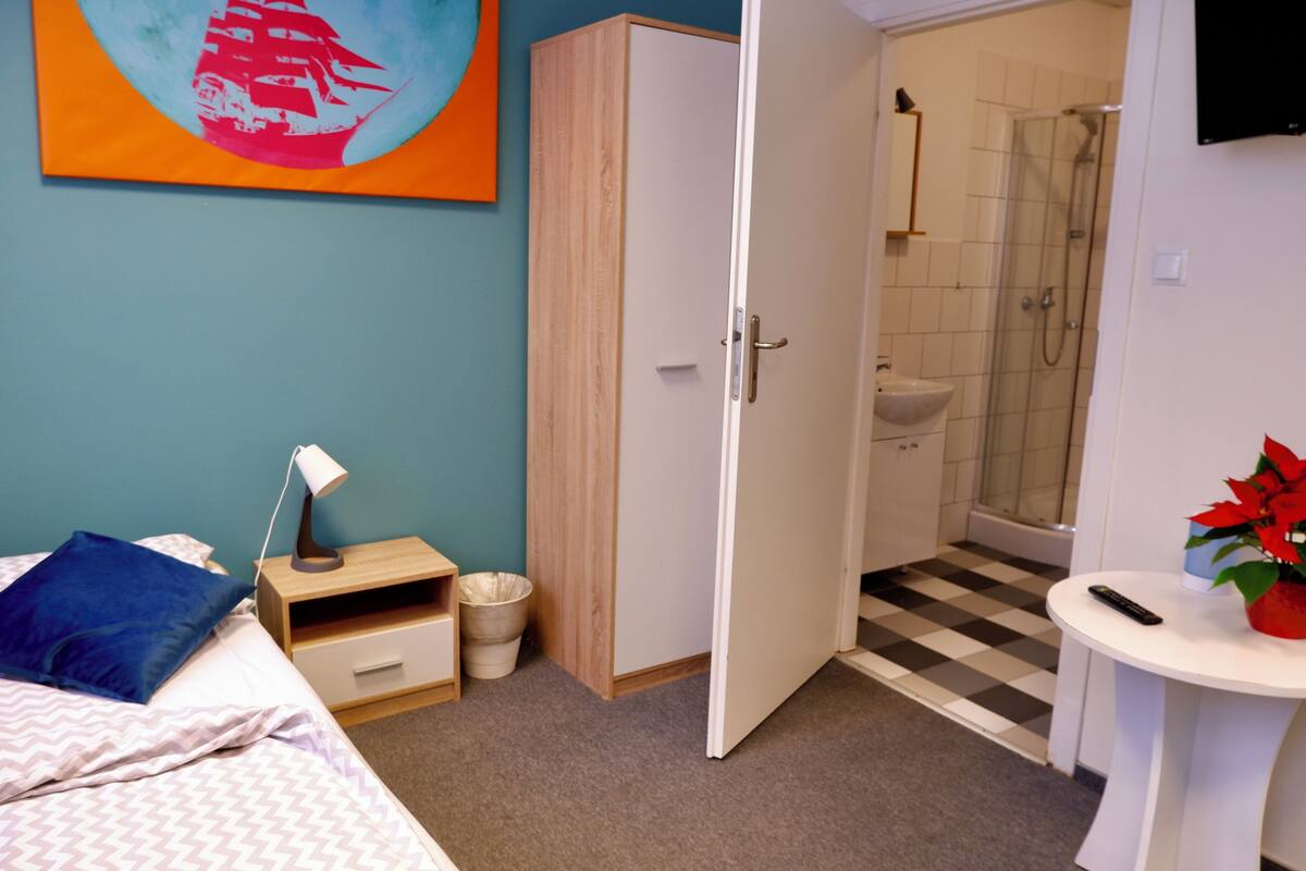 Un dormitorio con cama, mesita de noche, lámpara y armario.