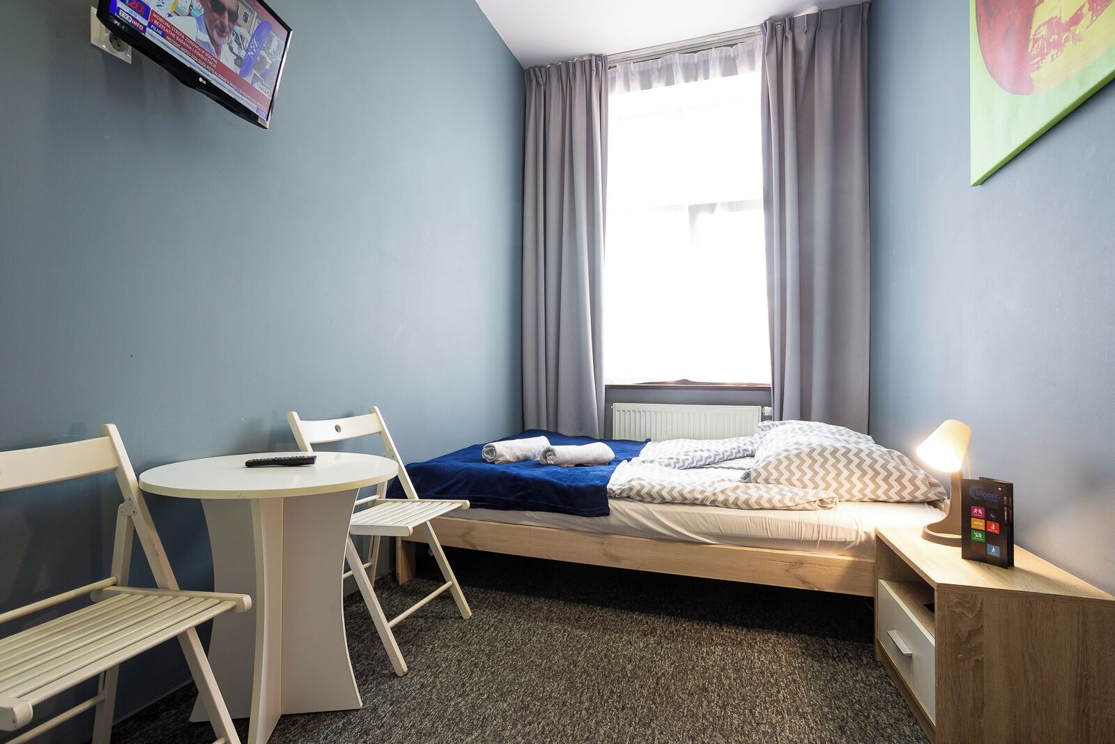 A compact hotel room with a single bed, a small table, and a chair.