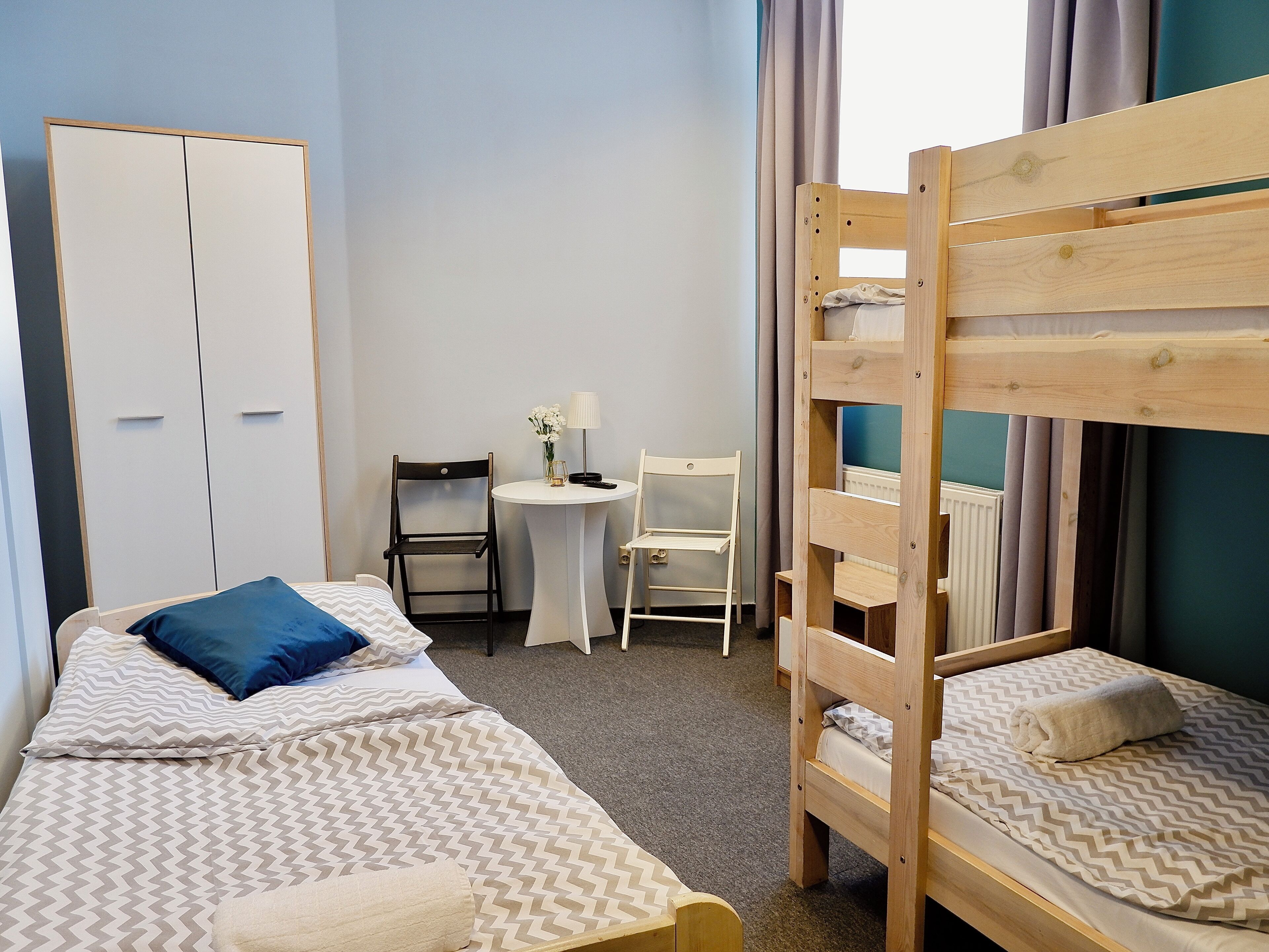 A room with bunk beds, a desk, chairs, and a wardrobe.