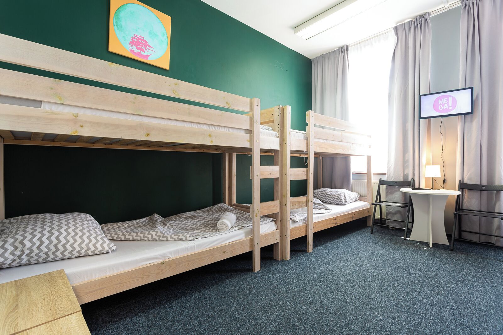 A room with bunk beds, a desk, a chair, a television, and a window with curtains.