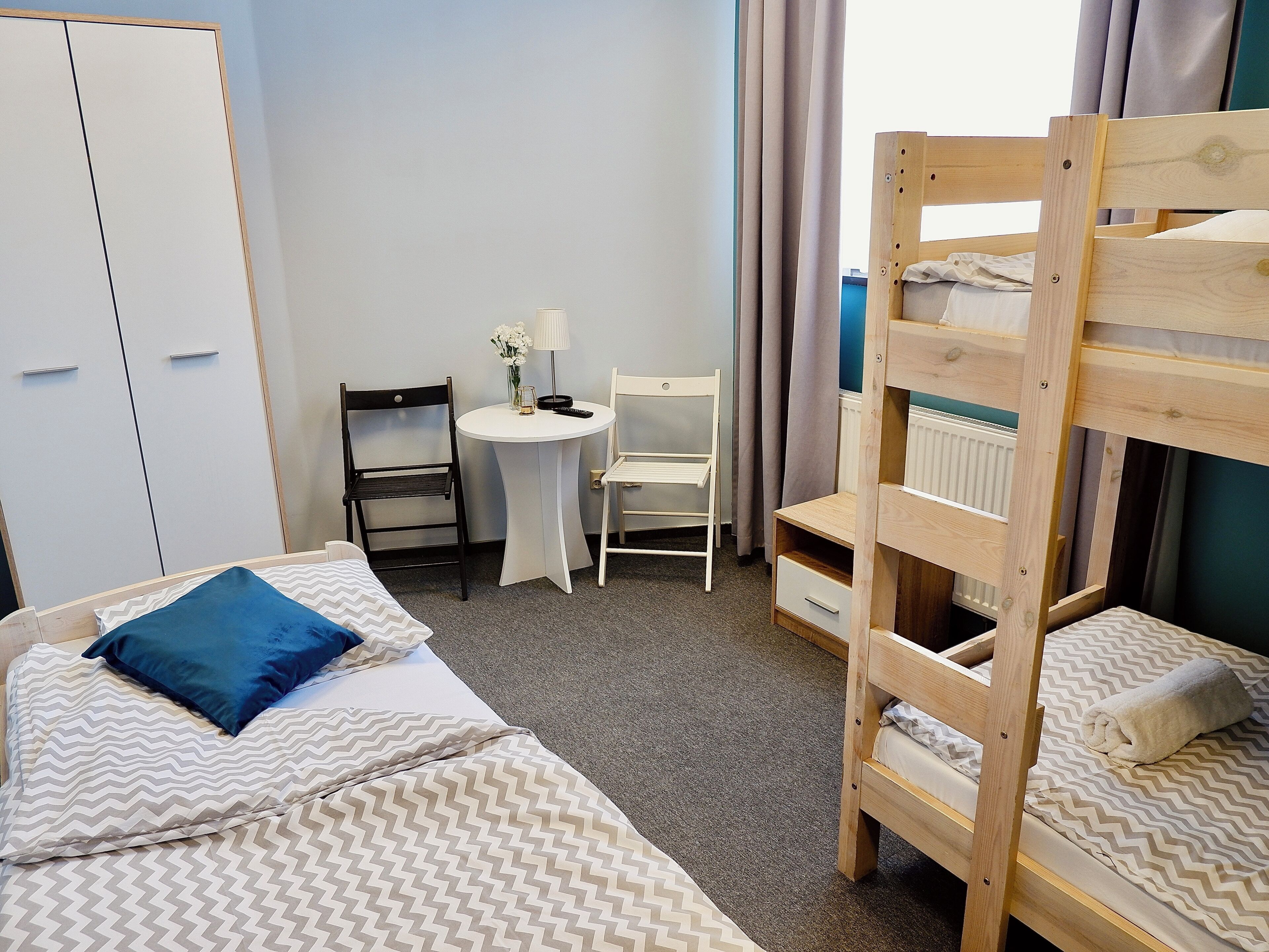 A room with bunk beds, a desk, a chair, and a wardrobe.