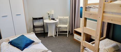 A room with bunk beds, a desk, a chair, and a wardrobe.