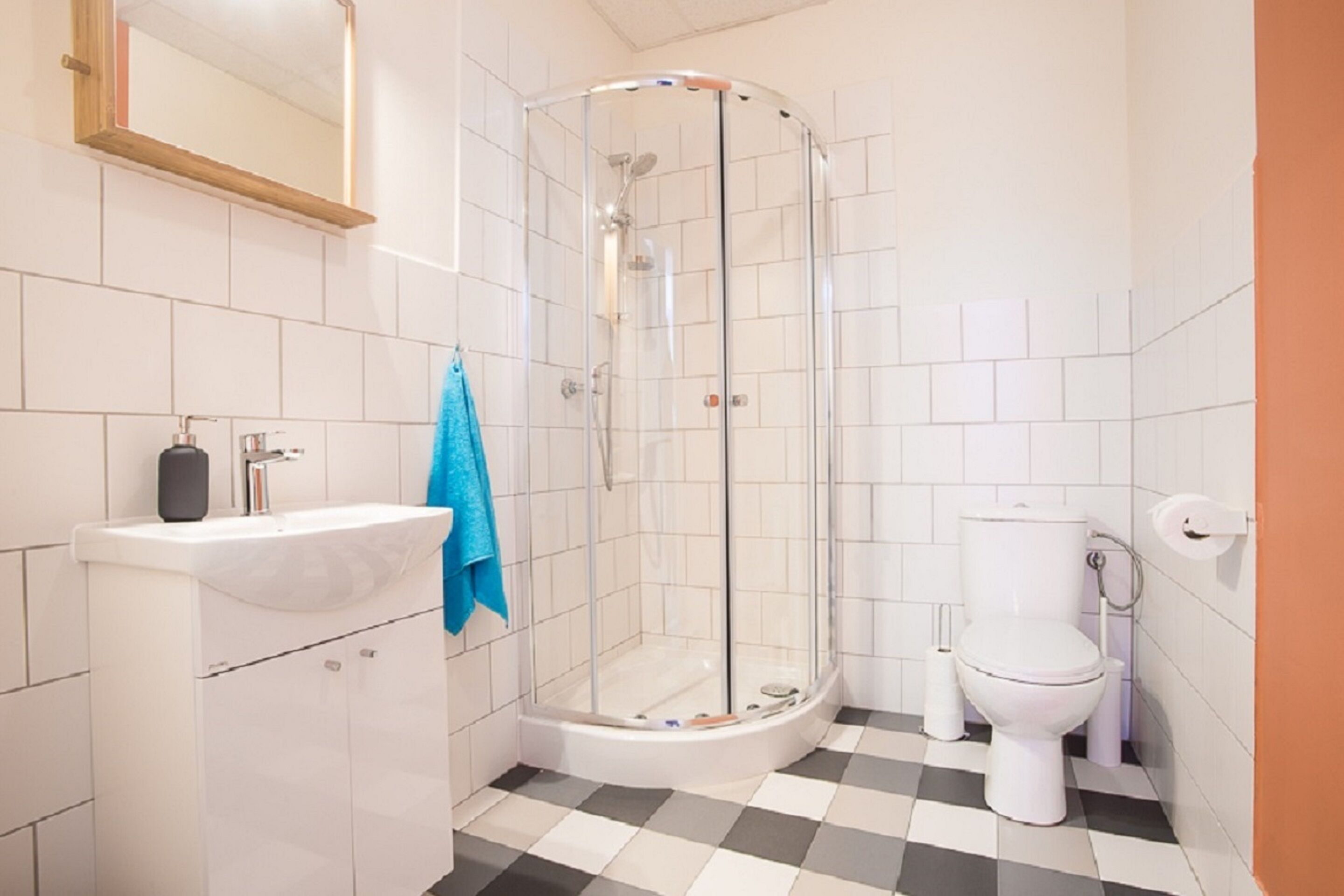 A bathroom with a glass shower enclosure, a sink with a towel, and a toilet.