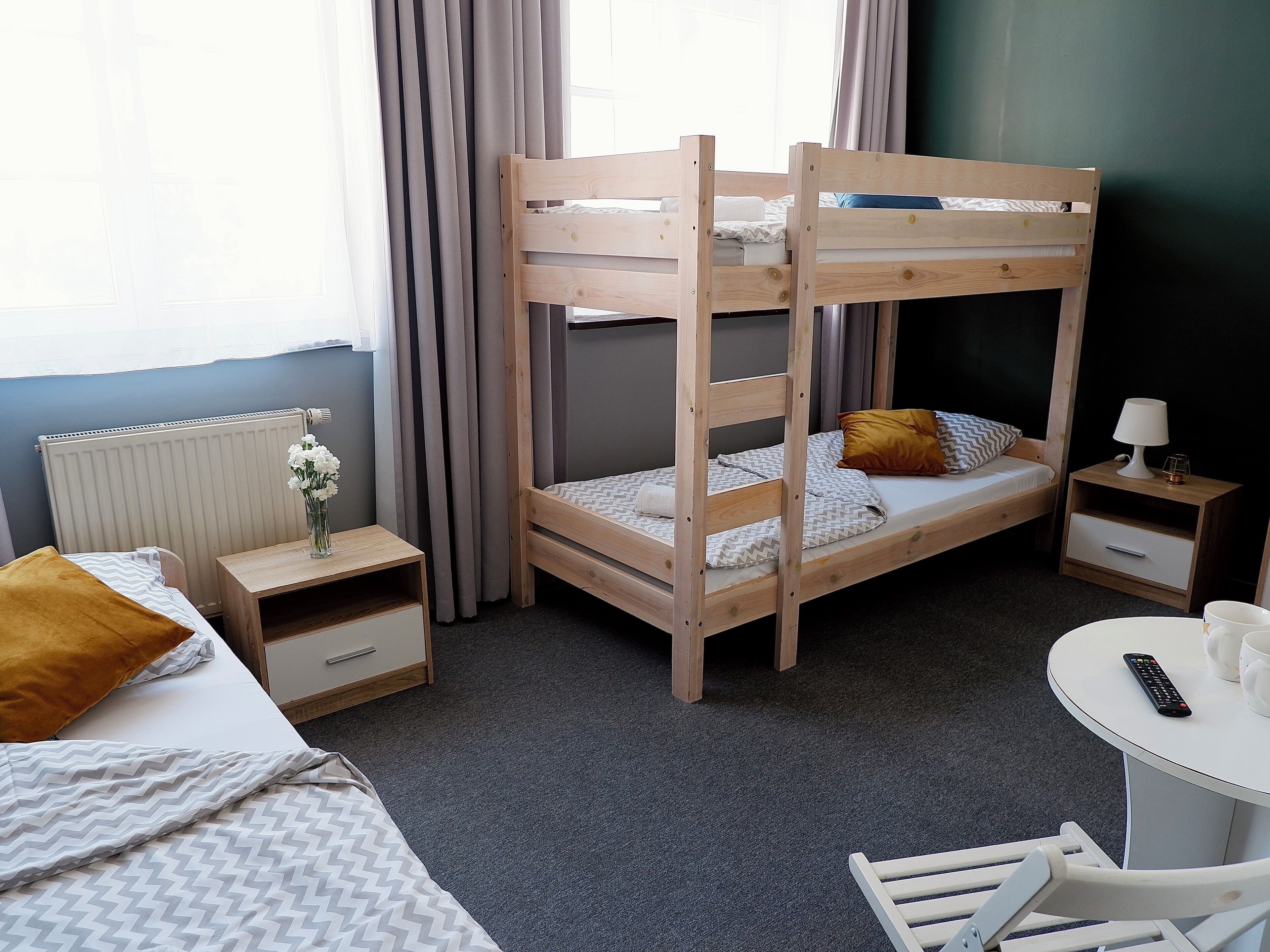 Et soveværelse med køjeseng, skrivebord, stol og et lille bord med lampe.