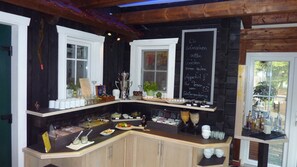 A rustic kitchen with wooden cabinets, a chalkboard menu, and various food items displayed on the counter.